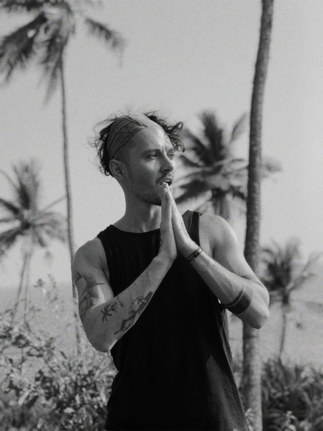 Andrei with his hands together among palm trees, black and white